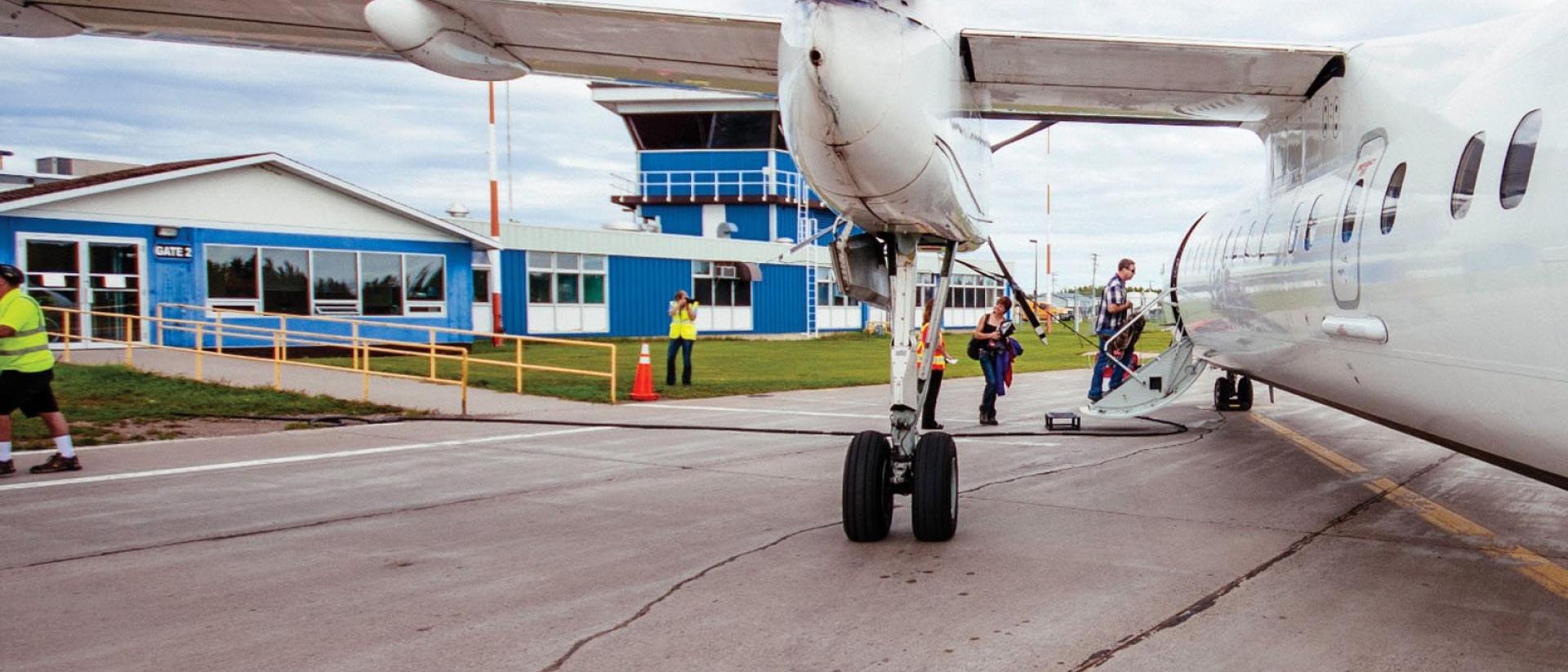 Two people boarding a plane on the runway.