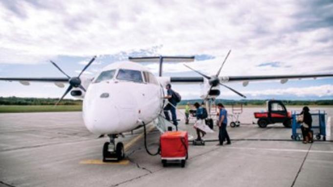 Plane being fuelled as passengers board by stairs on the runway.